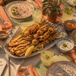 Barbecue entre amis sur grande table nappée, grillades et salades