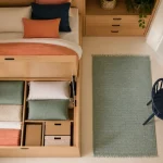 Lit pour petit chambre coffre en bois clair, linge plié et rangement